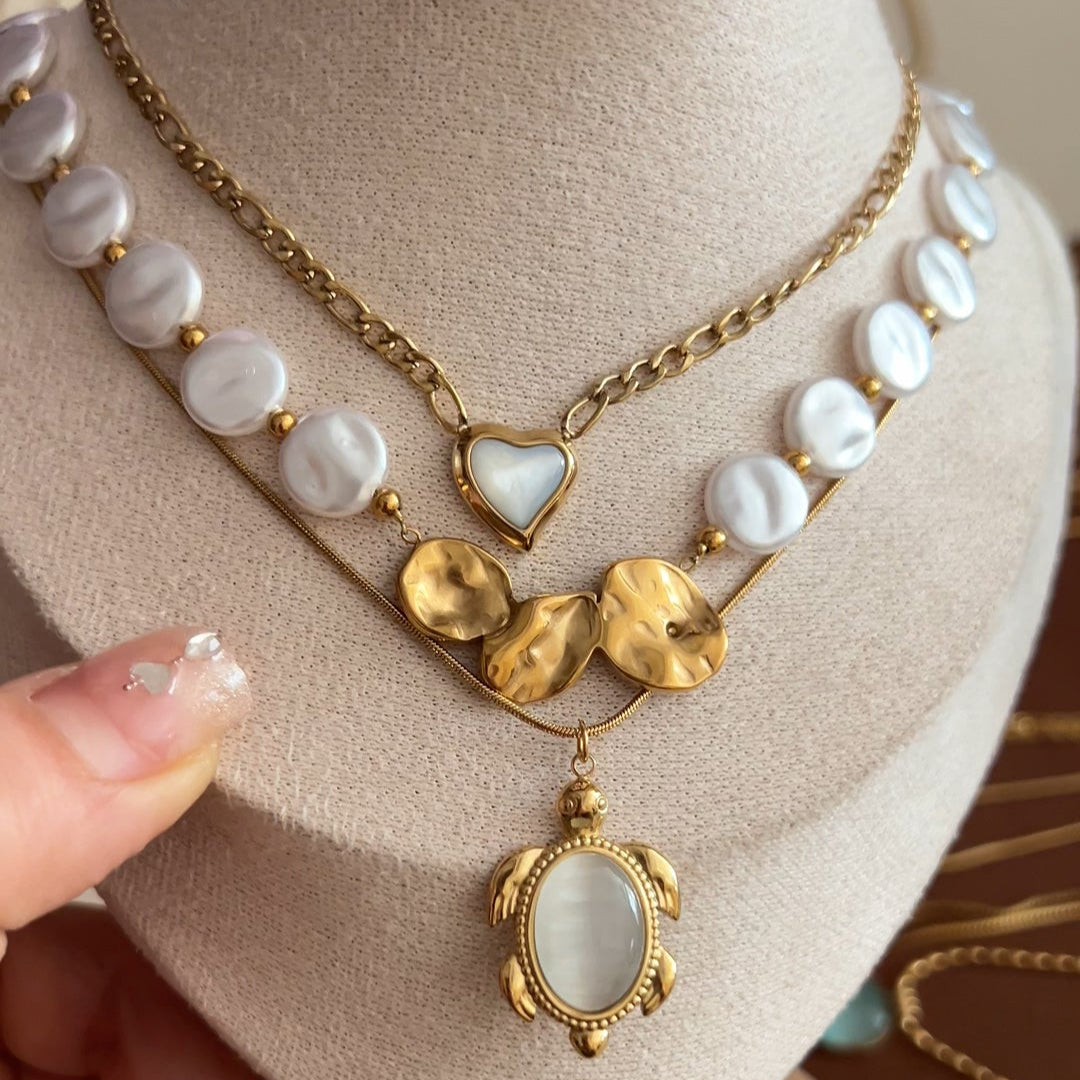 Layered gold-tone necklace set with turtle pendant, heart charm, and pearl-style beads
